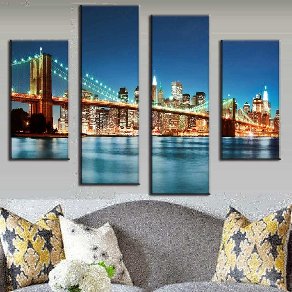 Brooklyn Bridge In Blue Night - 4-piece canvas wall art showing illuminated bridge and Manhattan skyline reflecting on East River at dusk with glowing city lights and turquoise water